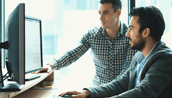 Two people working together at computer monitors.